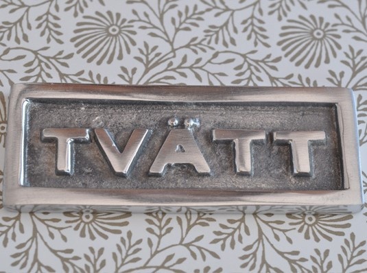 Sign with frame, TVÄTT, 9 x H 3,5 cm, Exmez, Sand-cast aluminum